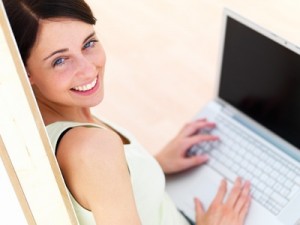 Closeup portrait of a happy young woman using laptop