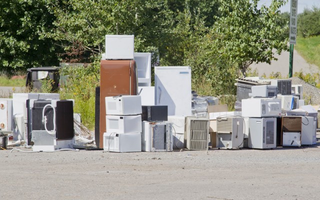 A stack of old appliances such as refrigerators freezers and air conditioners stacked up in a pile at a recycling garbage dump.