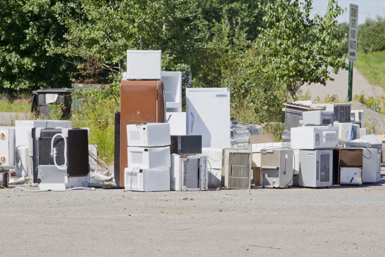 A stack of old appliances such as refrigerators freezers and air conditioners stacked up in a pile at a recycling garbage dump.